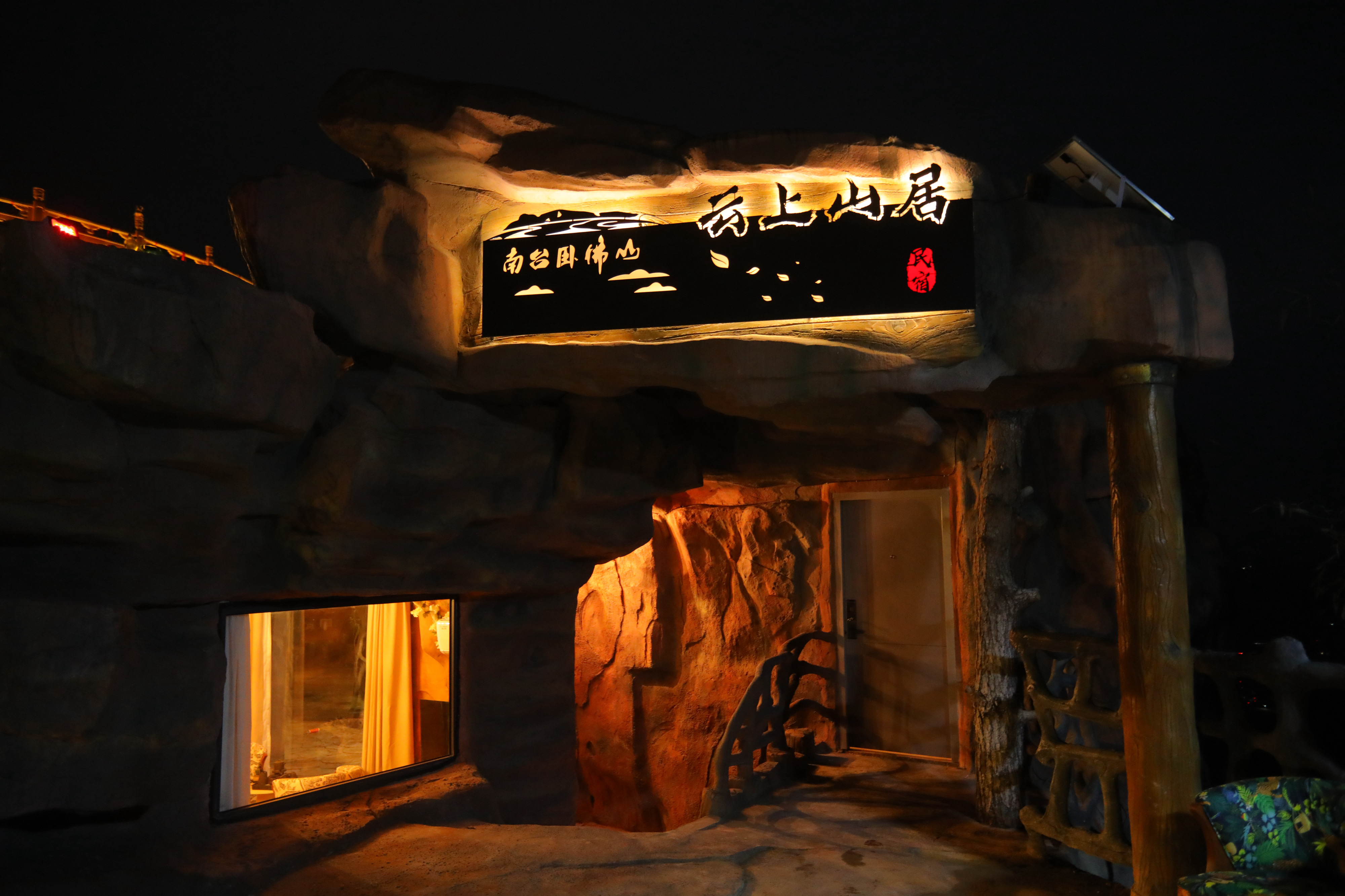 南台卧佛山云上山居悬崖民宿夜景，岩洞造型建筑依山而建，灯光温暖